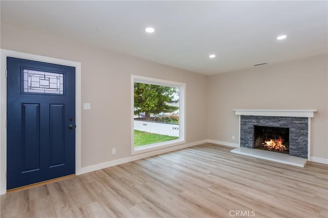 foyer entrance with visible vents, baseboards, light wood-style floors, a fireplace, and recessed lighting