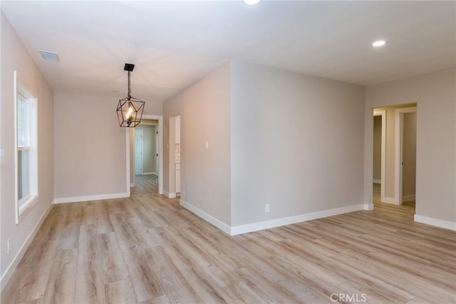 spare room with an inviting chandelier and light hardwood / wood-style flooring