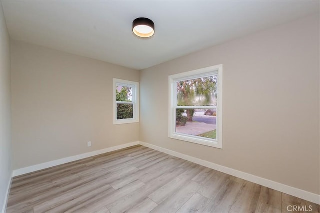 spare room featuring light wood-style floors and baseboards