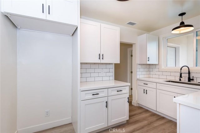 kitchen with light wood-style floors, white cabinetry, light countertops, and a sink