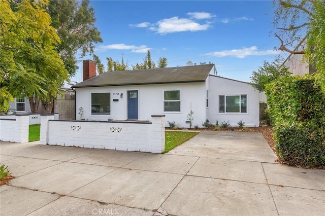 single story home with a fenced front yard, a chimney, and stucco siding