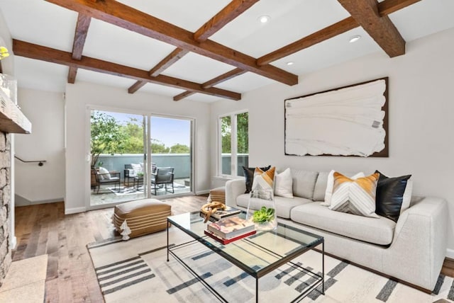 living room featuring beamed ceiling, a fireplace, coffered ceiling, and light hardwood / wood-style floors