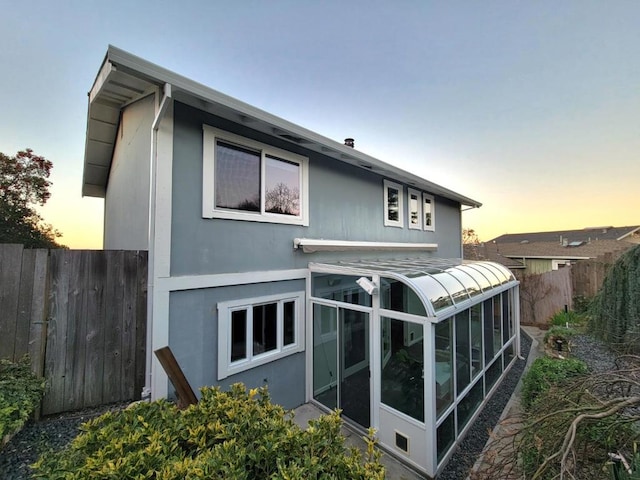 back house at dusk featuring a sunroom