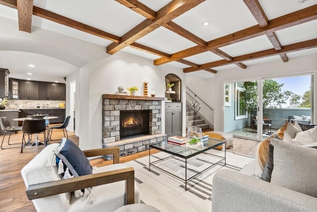 living room with coffered ceiling, beam ceiling, a fireplace, and light hardwood / wood-style floors