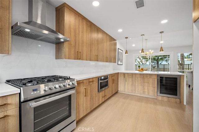 kitchen featuring wine cooler, stainless steel appliances, kitchen peninsula, and wall chimney exhaust hood