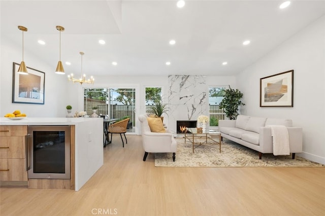 living room with a premium fireplace, vaulted ceiling, wine cooler, and light wood-type flooring