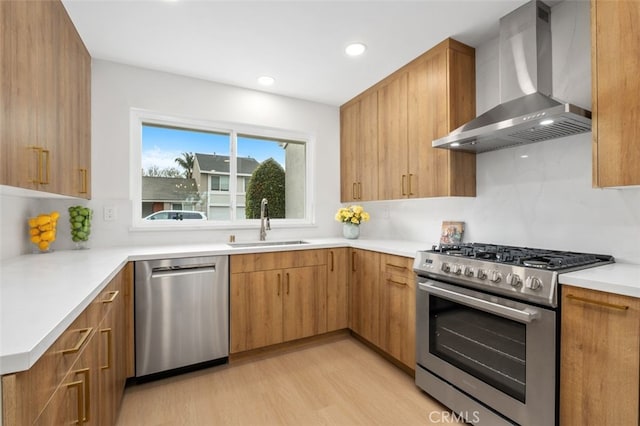 kitchen with wall chimney range hood, light hardwood / wood-style floors, sink, and appliances with stainless steel finishes