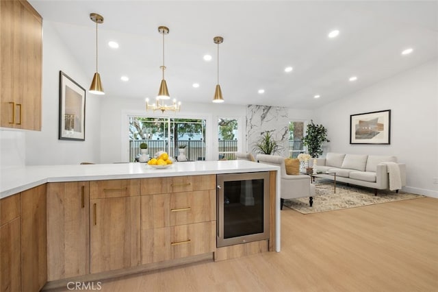 kitchen with light hardwood / wood-style flooring, hanging light fixtures, wine cooler, vaulted ceiling, and kitchen peninsula