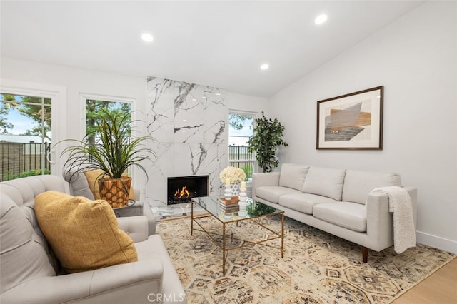 living room featuring wood-type flooring, a premium fireplace, and vaulted ceiling