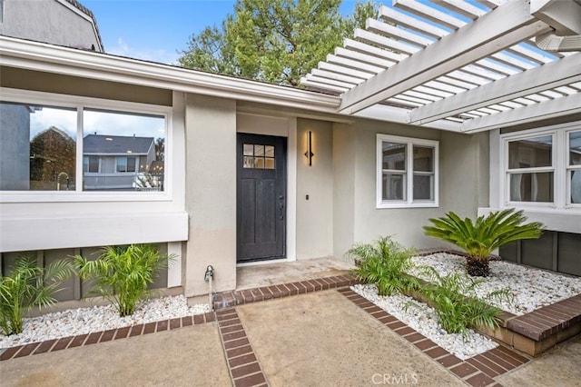 view of exterior entry with a pergola and a patio area