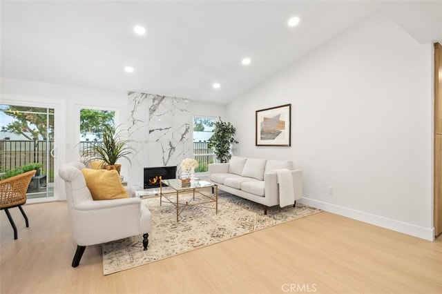 living room with lofted ceiling, a high end fireplace, and light wood-type flooring