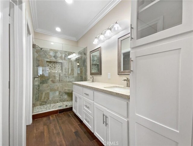 bathroom featuring a shower with door, crown molding, wood-type flooring, and vanity