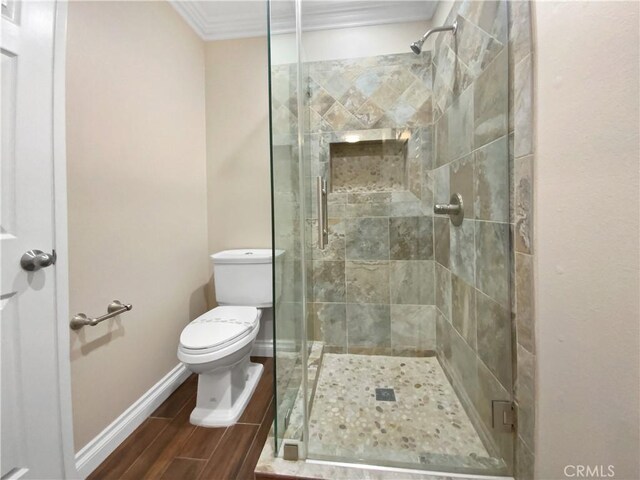 bathroom with ornamental molding, toilet, and a shower with door