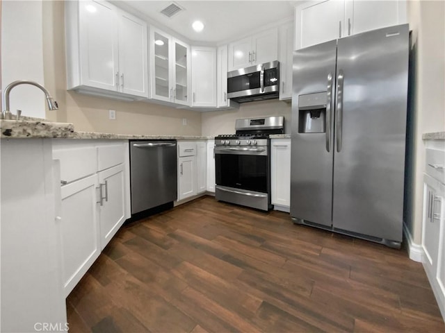 kitchen with sink, white cabinetry, appliances with stainless steel finishes, dark hardwood / wood-style floors, and light stone countertops