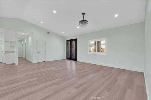 unfurnished living room featuring french doors, vaulted ceiling, and light wood-type flooring