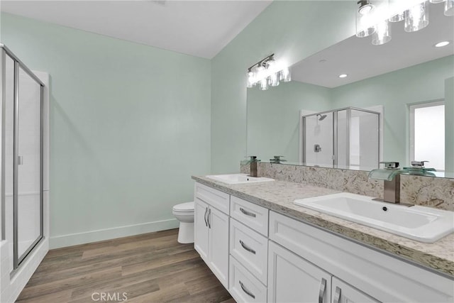 bathroom with vanity, hardwood / wood-style floors, a shower with door, and toilet