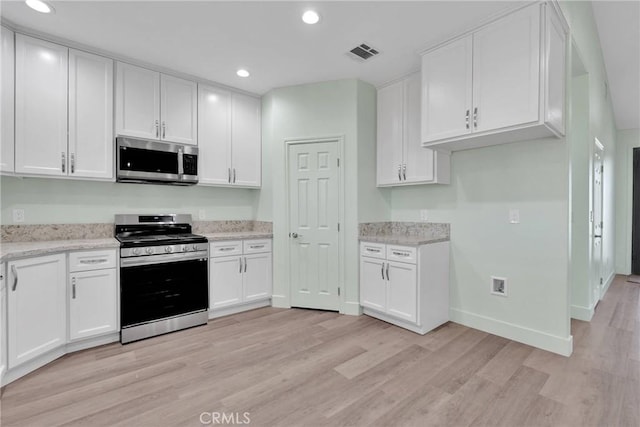 kitchen featuring white cabinetry, appliances with stainless steel finishes, light stone counters, and light hardwood / wood-style flooring