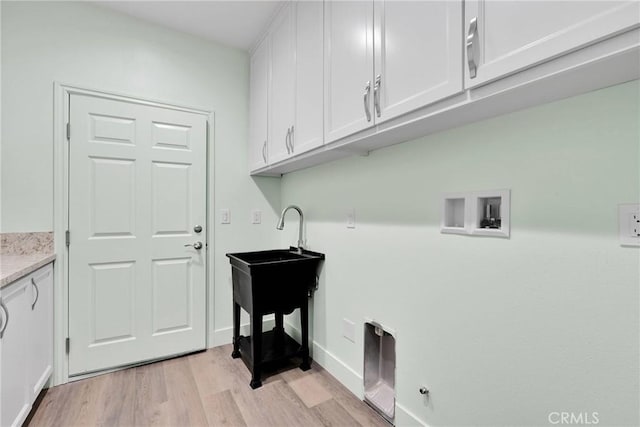 washroom with cabinets, hookup for a washing machine, and light hardwood / wood-style flooring