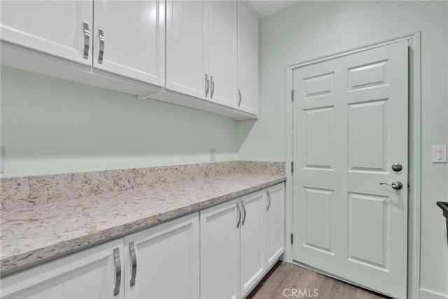 kitchen with white cabinetry, light stone countertops, and light hardwood / wood-style floors