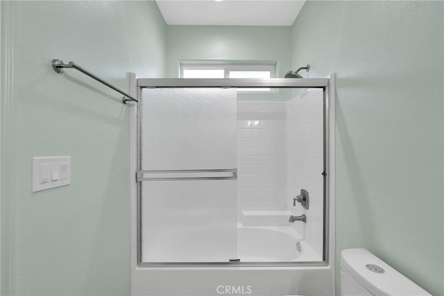 bathroom with enclosed tub / shower combo and toilet