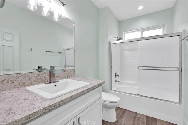 full bathroom featuring vanity, hardwood / wood-style floors, enclosed tub / shower combo, and toilet