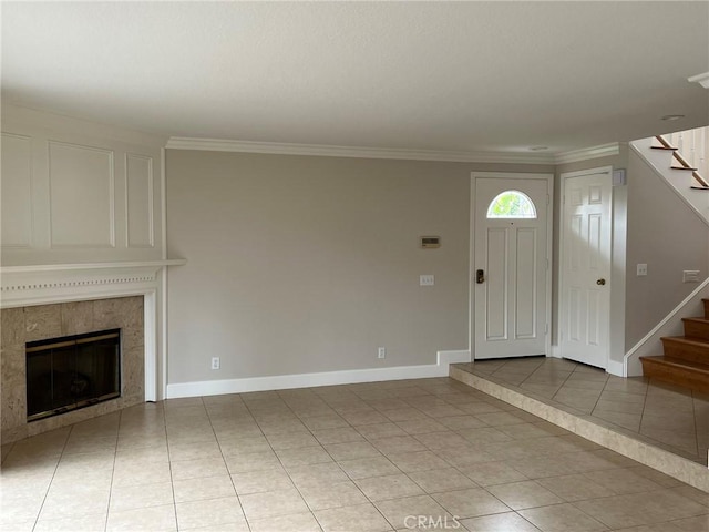 foyer featuring a tiled fireplace, light tile patterned floors, and ornamental molding