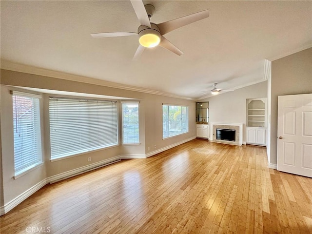 unfurnished living room featuring vaulted ceiling, light hardwood / wood-style flooring, ornamental molding, ceiling fan, and built in shelves