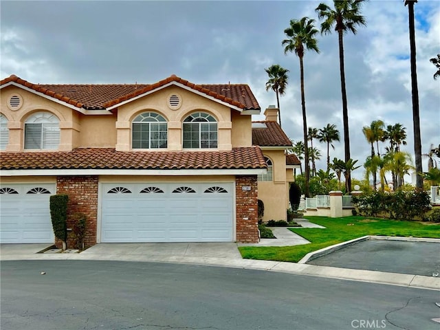 mediterranean / spanish home featuring a garage and a front yard