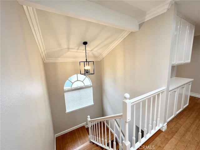 staircase with hardwood / wood-style floors, a notable chandelier, and ornamental molding