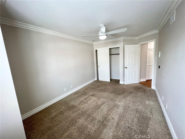 unfurnished bedroom featuring crown molding, ceiling fan, dark colored carpet, a textured ceiling, and a closet