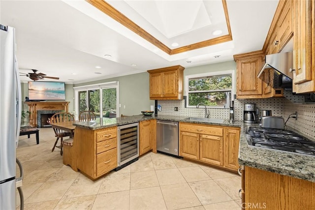 kitchen featuring sink, dark stone countertops, stainless steel appliances, wine cooler, and kitchen peninsula