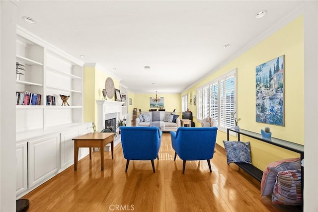 living room with crown molding, an inviting chandelier, built in features, and light wood-type flooring