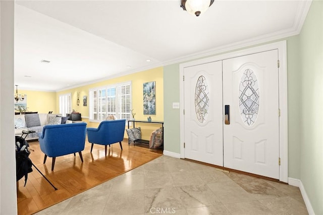 foyer entrance featuring crown molding, a chandelier, and light wood-type flooring