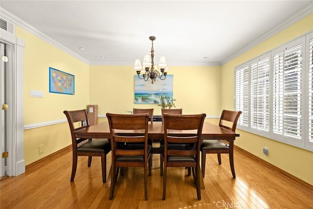 dining room with ornamental molding, an inviting chandelier, and light wood-type flooring