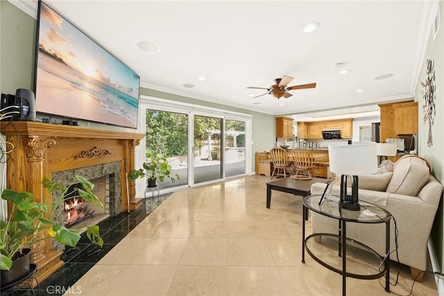 tiled living room with crown molding, ceiling fan, and a premium fireplace