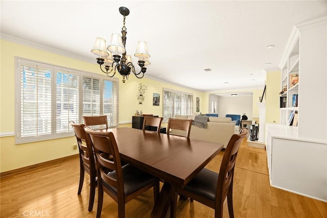 dining room with a notable chandelier, crown molding, and light wood-type flooring