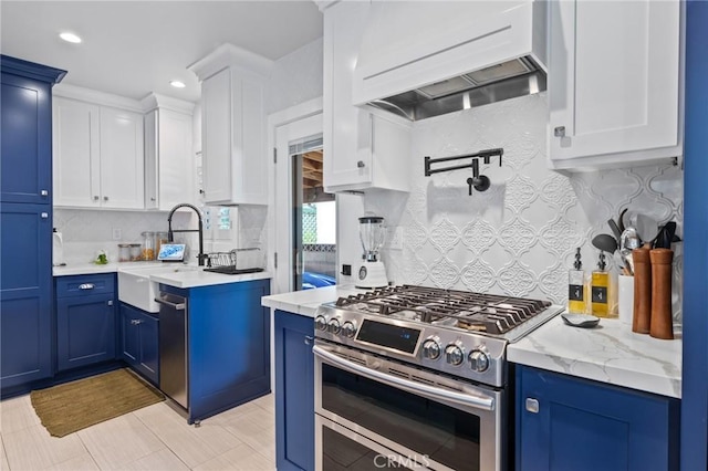 kitchen with blue cabinetry, appliances with stainless steel finishes, sink, and custom range hood