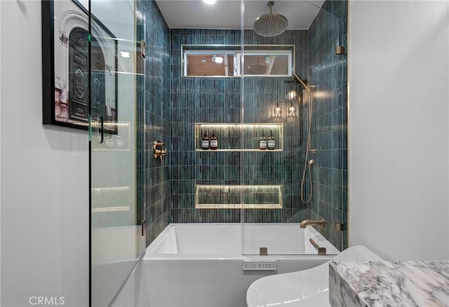 bathroom featuring toilet and shower / bath combination with glass door