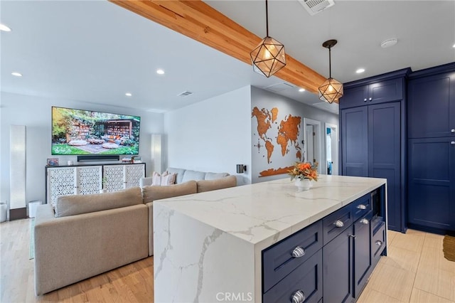 kitchen featuring light stone counters, decorative light fixtures, and a center island