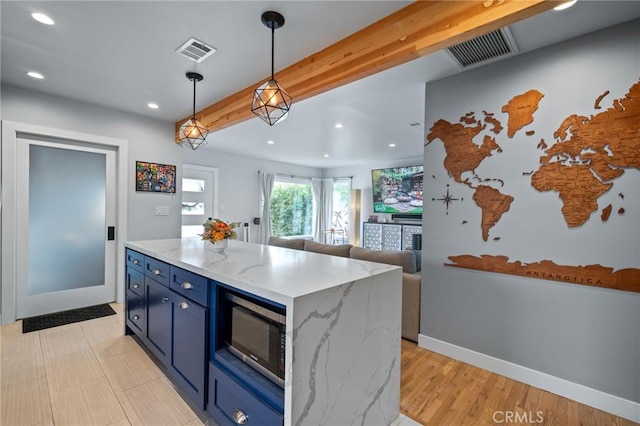 kitchen featuring hanging light fixtures, beam ceiling, blue cabinets, light stone countertops, and a kitchen island