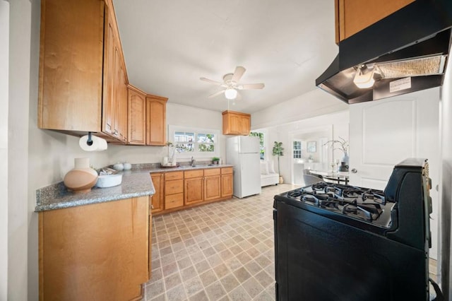 kitchen featuring black gas range oven, sink, ceiling fan, range hood, and white fridge