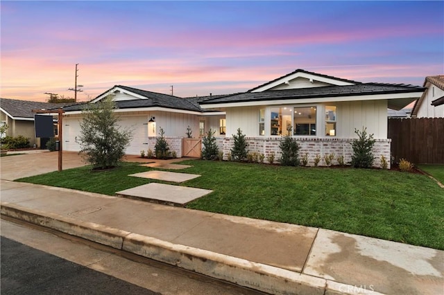 single story home featuring a garage and a lawn