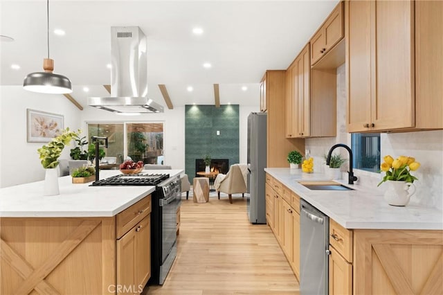 kitchen featuring a fireplace, sink, hanging light fixtures, island exhaust hood, and stainless steel appliances