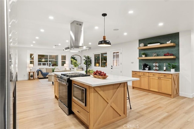 kitchen featuring a breakfast bar area, gas range, decorative light fixtures, a kitchen island, and island exhaust hood