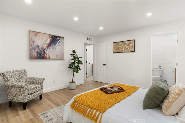 bedroom with connected bathroom and light wood-type flooring