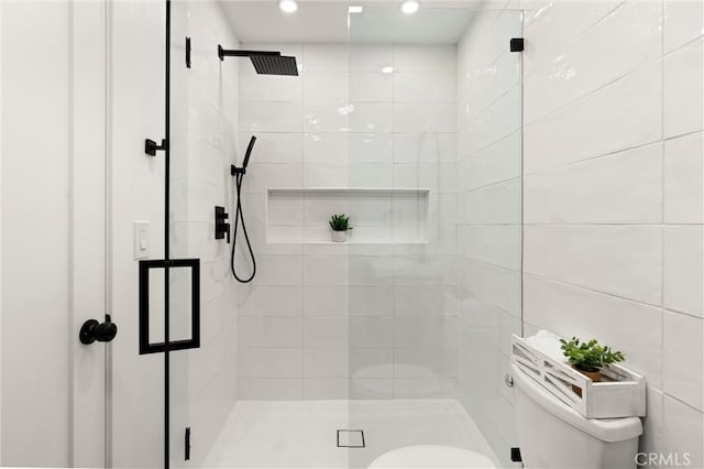 bathroom featuring a shower with door, tile walls, and toilet