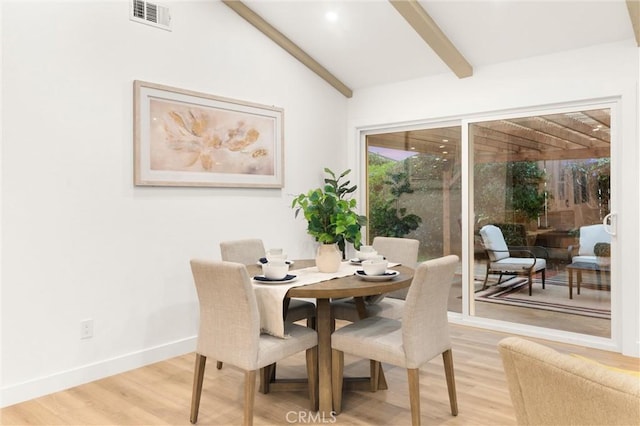 dining area with hardwood / wood-style flooring and vaulted ceiling with beams