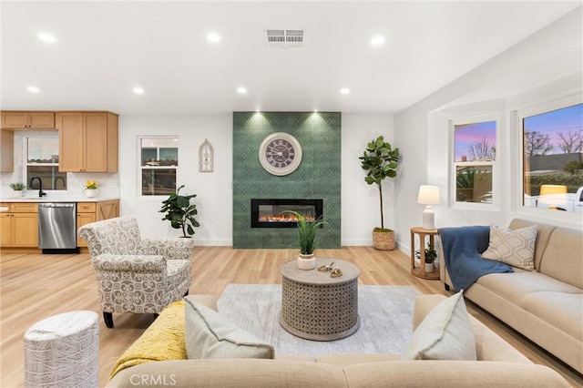 living room featuring sink, a fireplace, and light hardwood / wood-style floors