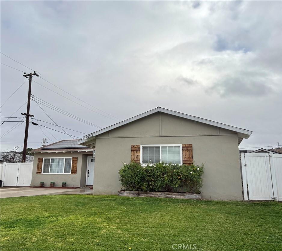 single story home with a front lawn and solar panels