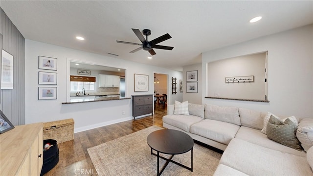 living room featuring dark wood-type flooring, sink, and ceiling fan